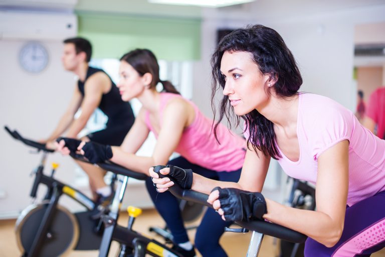 Three people at group indoor cycling class at sports complex