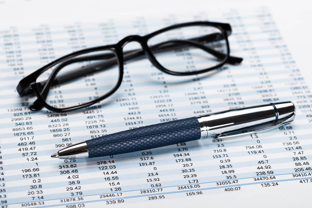 Financial data sheet with glasses and pen.