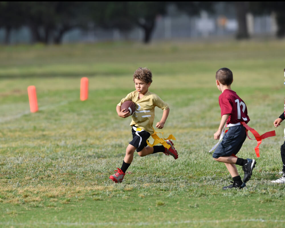 Flag football player running past defender with the ball.