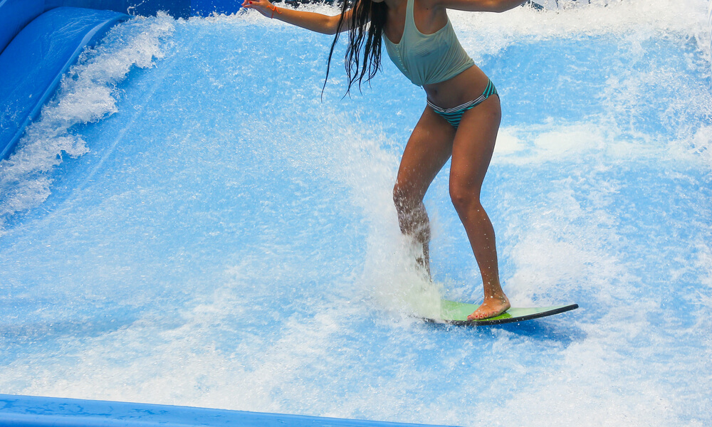 Young woman surfing in indoor wave pool