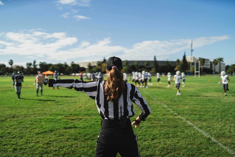 Closeup of an American football referee standing on the field watching the game.