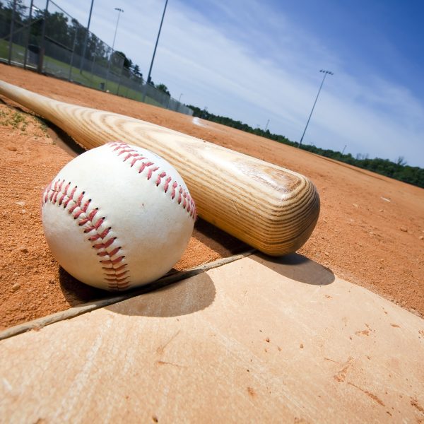 Baseball and bat on home plate of a ballpark